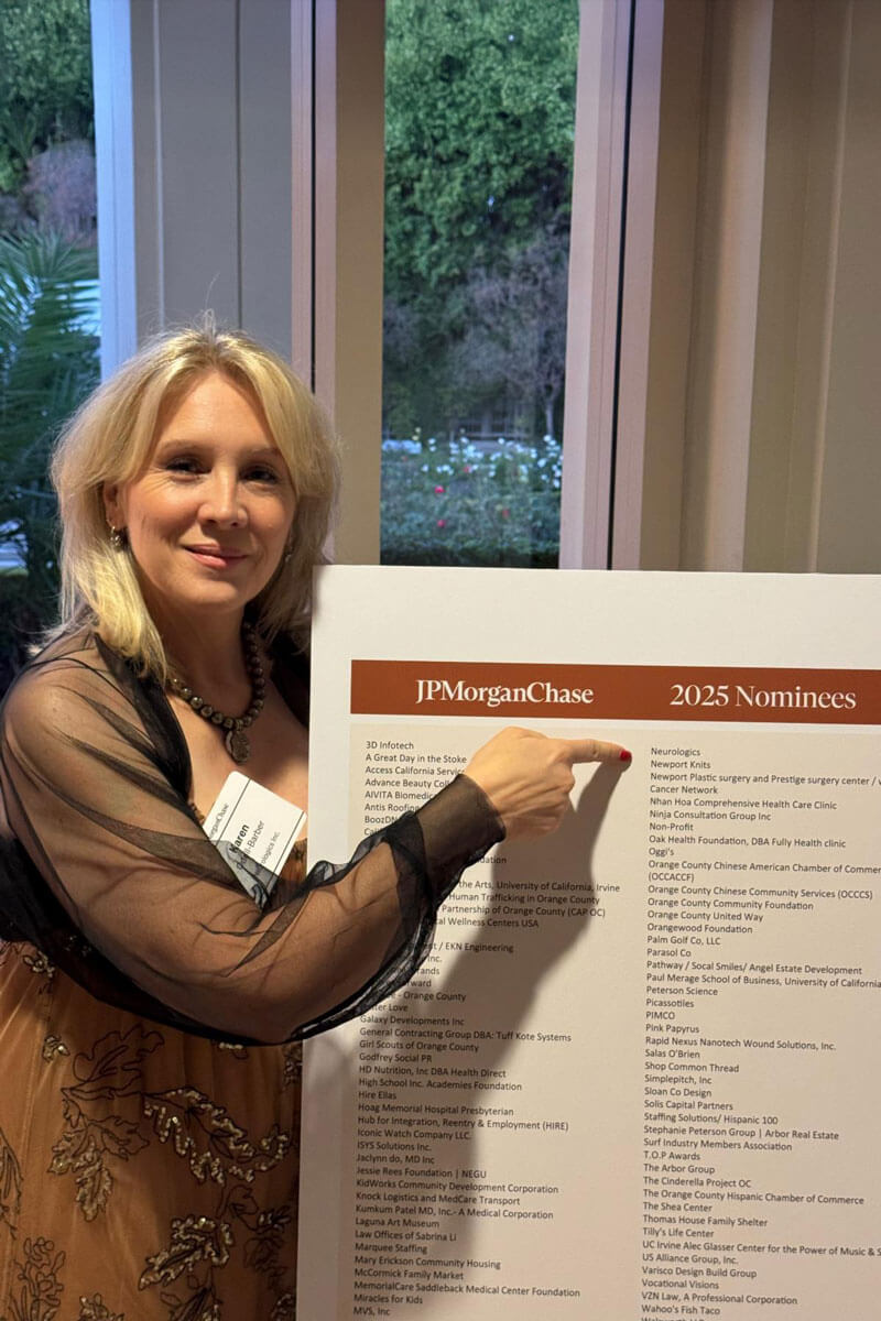 Three people stand together on a golf course smiling for a photo, with one holding a golf club.