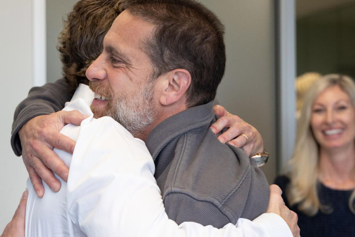 Two people smile and pose together in a casual indoor event setting.