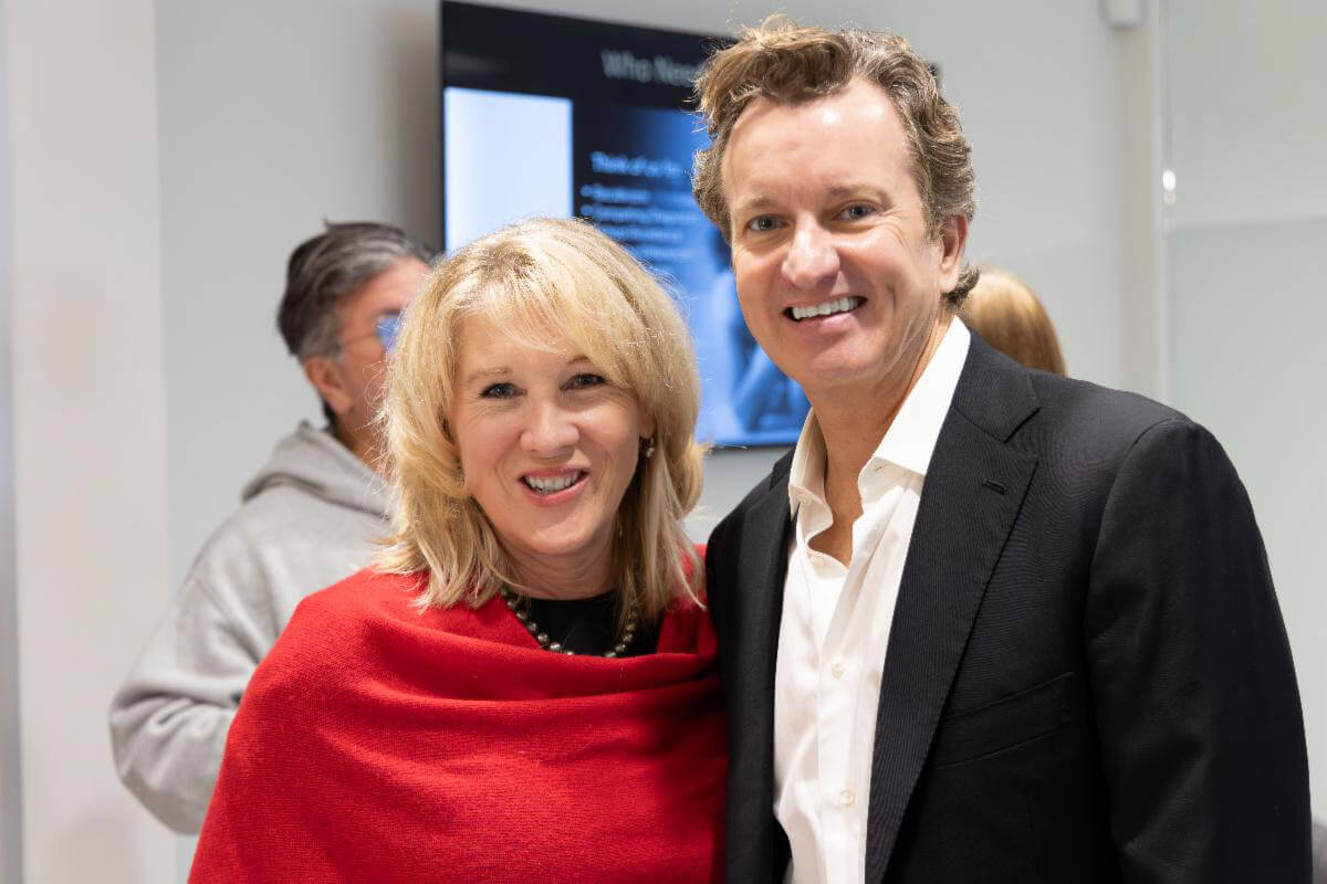 Two people stand close together smiling at an event, posing for a casual photo indoors.