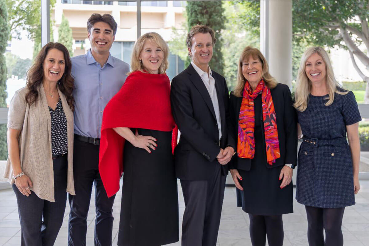 A group of people stand together smiling in a well-lit indoor space during an event.
