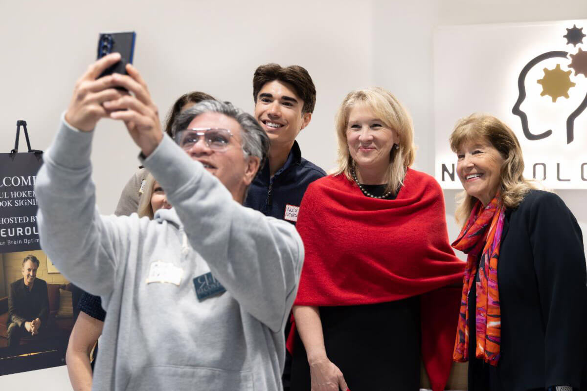 A group of attendees gather closely while taking a selfie together at an indoor event.