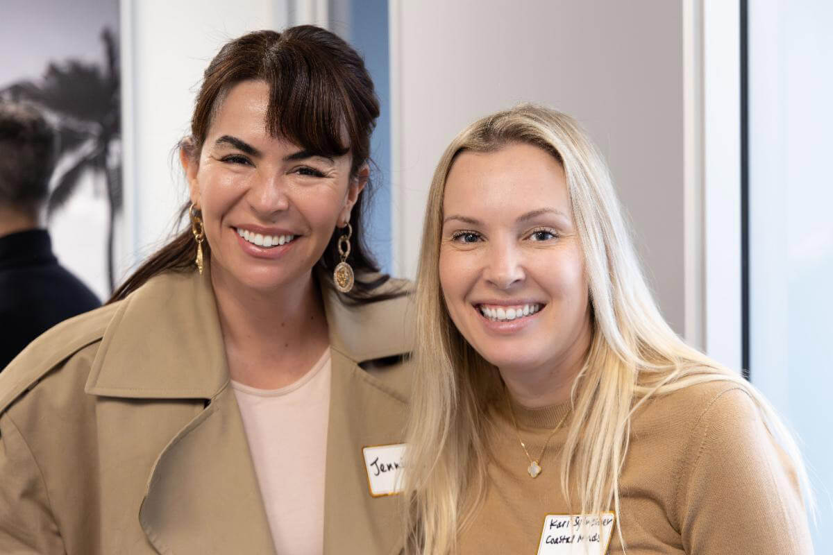 Two people stand side by side smiling for a photo at a professional indoor event.